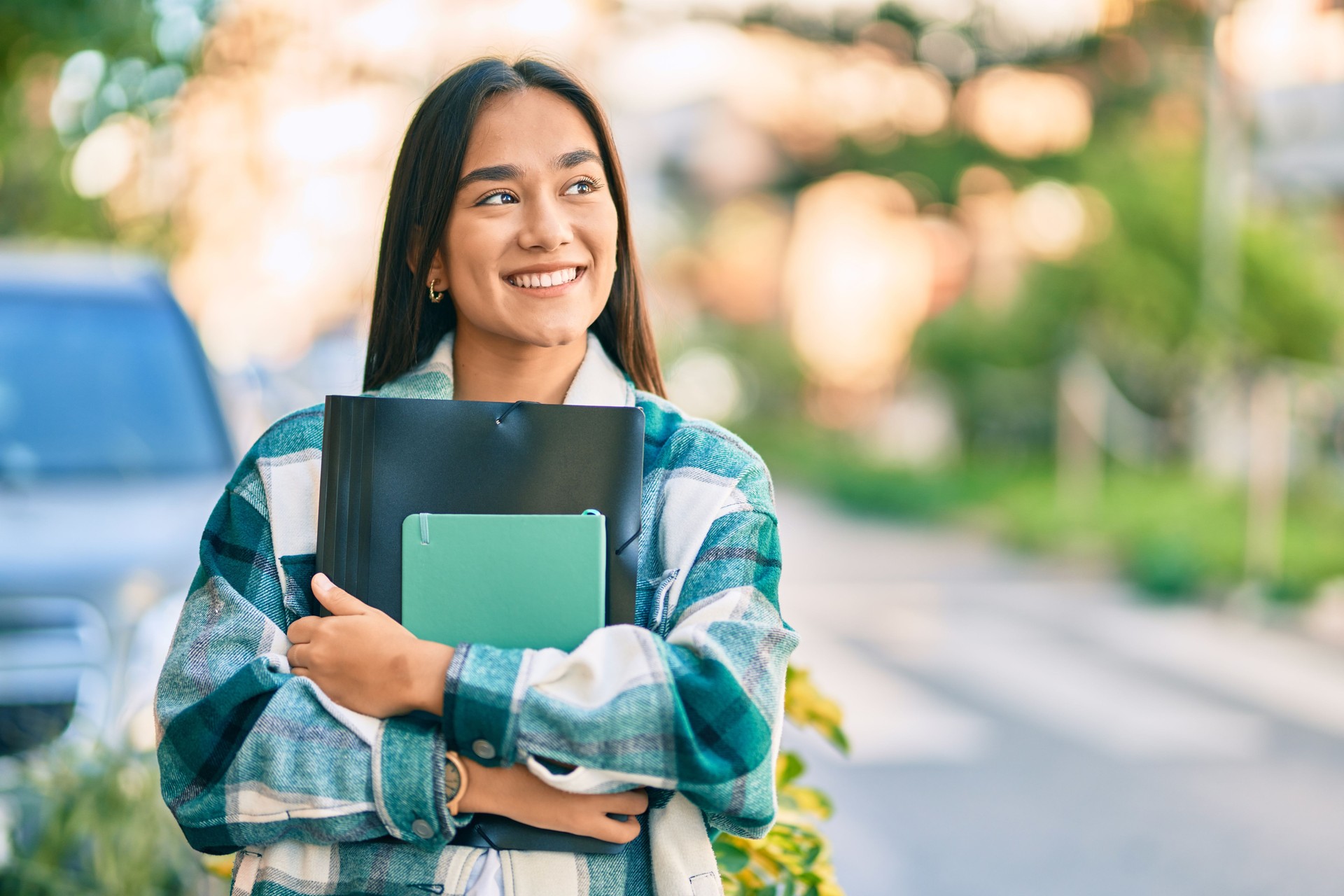 Young latin student girl smiling happy holding folder on her way to TRIO and GEAR UP