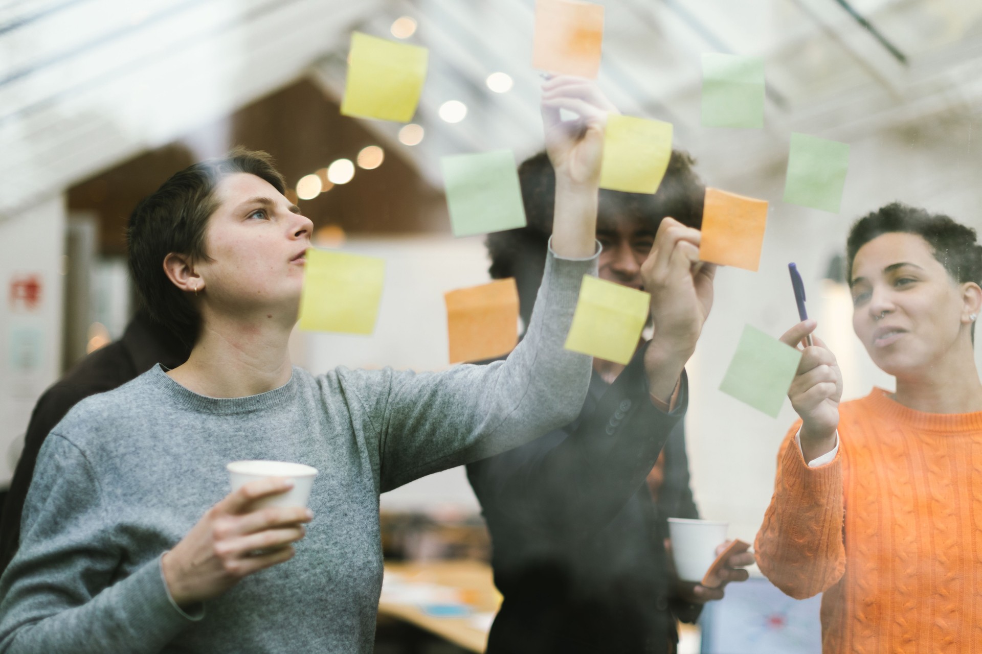 teamwork, young entrepreneurs make up their mind by working with adhesive notes attached to the glass of the startup's office