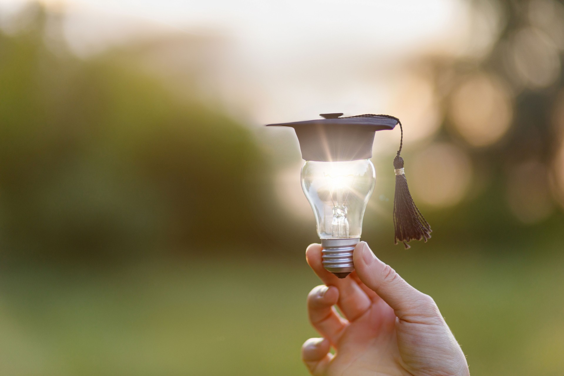 A hand shows a light bulb with an academic cap.