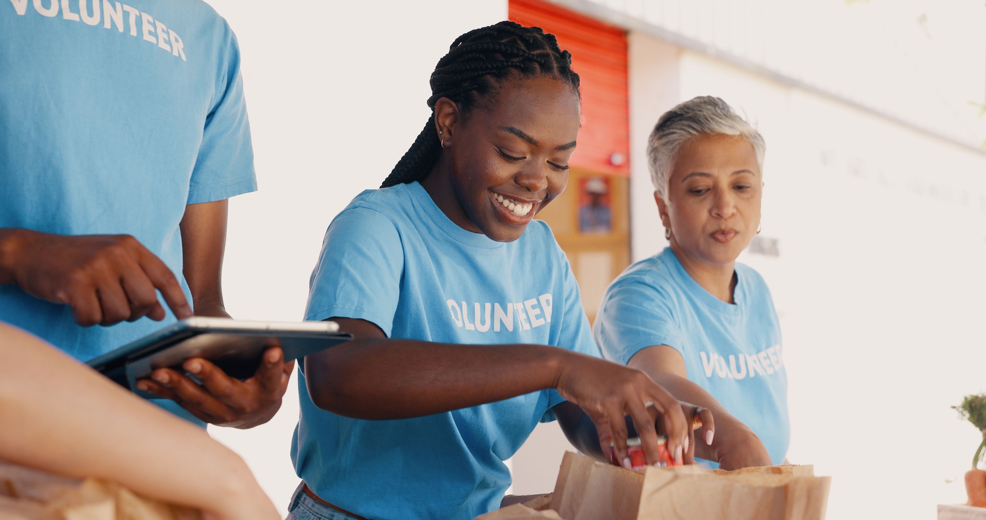 Volunteering at non profit, group of people and tablet for food donation, community service and poverty support with NGO checklist. Nonprofit manager, teamwork and groceries bag for distribution or charity project